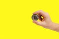 Bitcoin Coin Grasped in Hand on Yellow Backdrop. Symbolic of digital wealth, perfect for finance themed designs. Royalty Free Stock Photo