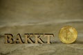 Bitcoin coin and next to wooden with BAKKT