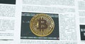 Bitcoin coin symbol in front of financial newspaper with stock market developmen