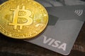 Bitcoin coin and Visa bank card on a dark wooden background. BTC cryptocurrency. Blockchain technology. Close-up.