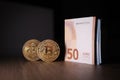 2 Bitcoin coins are next to a bundle of euro banknotes Royalty Free Stock Photo