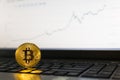 Bitcoin cryptocurrency coin standing on laptop keyboard with ascending chart on background Royalty Free Stock Photo