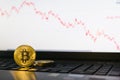 Bitcoin cryptocurrency coin standing on laptop keyboard with descending chart on background Royalty Free Stock Photo