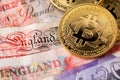 Bitcoin cryptocurrency coins on United Kingdom Pound Sterling banknotes. Royalty Free Stock Photo