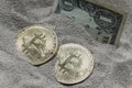 Bitcoin currency seen partially buried in Silicon Sand together with a One Dollar Banknote. Royalty Free Stock Photo