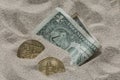 Bitcoin currency seen partially buried in Silicon Sand together with a One Dollar Banknote. Royalty Free Stock Photo