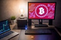 Bitcoin on desk with graphic and candlestick graph on screen Royalty Free Stock Photo