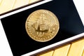 Bitcoin gold coin laying on a smartphone screen, closeup, top view. Golden coin on a mobile phone display, seen from above, app Royalty Free Stock Photo