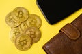 Bitcoin golden coin, wallet and smartphone on yellow background.