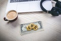 Bitcoin golden coins on a dollar banknotes. Office background. Cup of coffee, white laptop, mobile phone, and money. Money balance Royalty Free Stock Photo