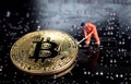 Bitcoin mining miniature worker, small figure holding mattock di