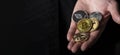 Bitcoin and other different cryptocurrency coins in male hand palm over black background with copy space for text