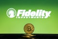 Fidelity logo on a computer screen with a stack of Bitcoin cryptocurency coins. Royalty Free Stock Photo