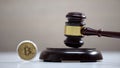Bitcoin on table, gavel standing on sound block, crypto currency legalization