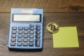 Bitcoin on a wooed surface and blue color calculator and empty memo note. Copy space. Finance and investment concept. Abstract Royalty Free Stock Photo