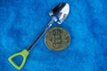 Bitcoin yellow coin and a small shovel on blue wool matter