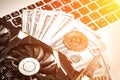 Bitcoins with dollar bills on laptop keyboard. Bitcoin. New virtual money. Video card, concept of mining. Sun flare Royalty Free Stock Photo