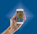 Bitcoins emerging from app on handheld smartphone Royalty Free Stock Photo