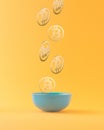 Bitcoins falling in blue bowl against orange background. Bitcoin wealth concept. Mining or blockchain technology for