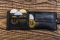 Bitcoins, litecoin and ethereum in black leather wallet on wooden background