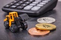 Bitcoins, miniature excavator and calculator. Cryptocurrency and international network payment. Finance concept Royalty Free Stock Photo