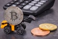 Bitcoins, miniature excavator and calculator. Cryptocurrency and international network payment. Finance concept Royalty Free Stock Photo