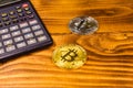 Bitcoins and scientific calculator on a wooden table