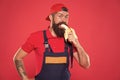 Bite banana. Handyman hungry. Have healthy snack. Bearded man in uniform and cap eating banana. Worker builder mechanic