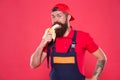 Bite banana. Handyman hungry. Have healthy snack. Bearded man in uniform and cap eating banana. Worker builder mechanic