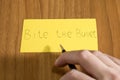 Bite the bullet handwrite on a yellow paper with a pen on a table Royalty Free Stock Photo