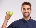 Bite into this. Portrait of a handsome young man holding an apple and smiing.