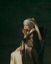 Medieval little girl as a lady with a pearl earring on dark studio background. Concept of comparison of eras, childhood