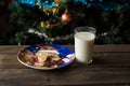 Bitten biscuit, crumbs and a glass of milk on a Christmas tree background