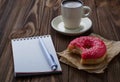 Bitten donut cup of coffee and notebook