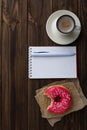 Bitten donut cup of coffee and notebook Royalty Free Stock Photo