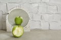 Bitten green apple near mirror with reflection of whole fruit on table, space for text Royalty Free Stock Photo