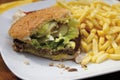 Bitten hamburger with chips in plate