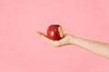 A bitten red apple in an open female palm on a pink background Royalty Free Stock Photo