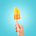 Bitten red frozen fruit ice cream popsicle in woman hand on blue background Royalty Free Stock Photo