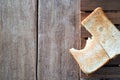 Bitten spread butter slice whole wheat sandwich bread on wooden plate on wood table