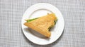 A bitten triangular sandwich with greens on a plate Royalty Free Stock Photo