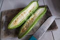 A bitter melon vegetable cut in half with a knife on a cutting board Royalty Free Stock Photo