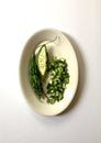 Bitter Melon: whole, halved, and sliced on a white oval platter