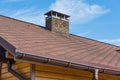 Bitumen asphalt roofing shingles and brick chimney pipe on a wooden house. Individual heating system. Rain gutter.