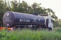 Bitumen tank trailer rides along the road against the backdrop o