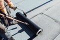 Bituminous membrane waterproofing system details and installation on flat rooftop. Professional construction worker installing