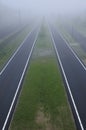 Bizarre perspective misty view by roads and train tracks with grass fields in between Royalty Free Stock Photo