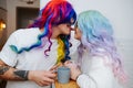 Bizzare looking couple in colorful wigs and sunglasses. Man licks girl& x27;s nose. Royalty Free Stock Photo