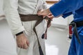 BJJ brazilian jui jutsu belt promotion close up on hands of unknown instructor black belt professor tie up brown belt on waist of