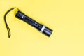 Blacc metal small tactical falshlight isoltaed on yellow background